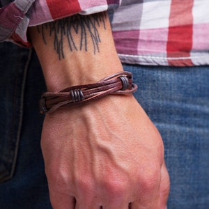 May include: A brown leather bracelet with a braided design and silver accents.