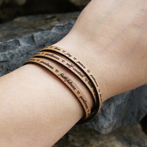 Puede incluir: Un brazalete de cuero marr&oacute;n con las palabras "amor, alegr&iacute;a, paz, paciencia, bondad, gentileza, fidelidad, mansedumbre, dominio propio, amor" grabadas en &eacute;l.