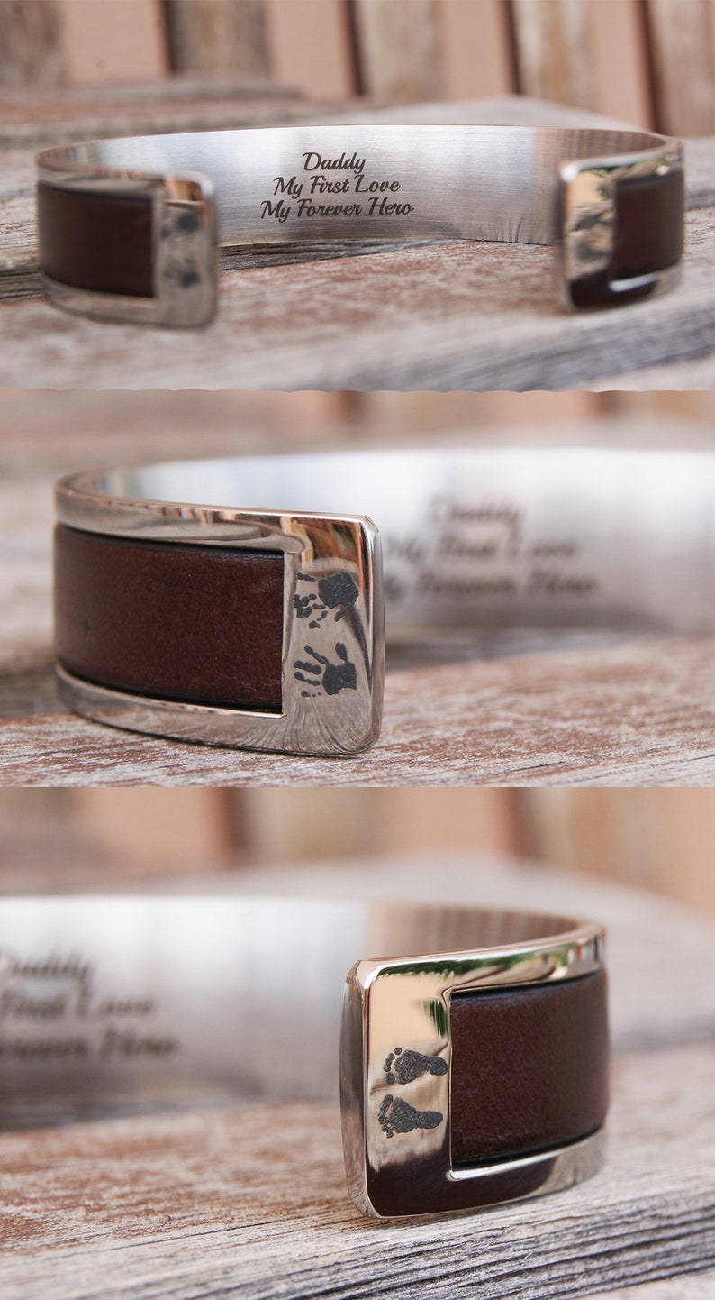 May include: A silver cuff bracelet with a brown leather band. The bracelet is engraved with the words "Daddy, My First Love, My Forever Hero." The leather band has a small imprint of two footprints.