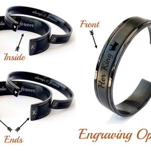 Op de afbeelding: Twee zwarte metalen armbanden met gegraveerde tekst. Een armband heeft de woorden "Her King" en een kroon aan de voorkant. De andere armband heeft de woorden "always & forever" en "forever" aan de buitenkant en een hart en de letter "K" aan de binnenkant.