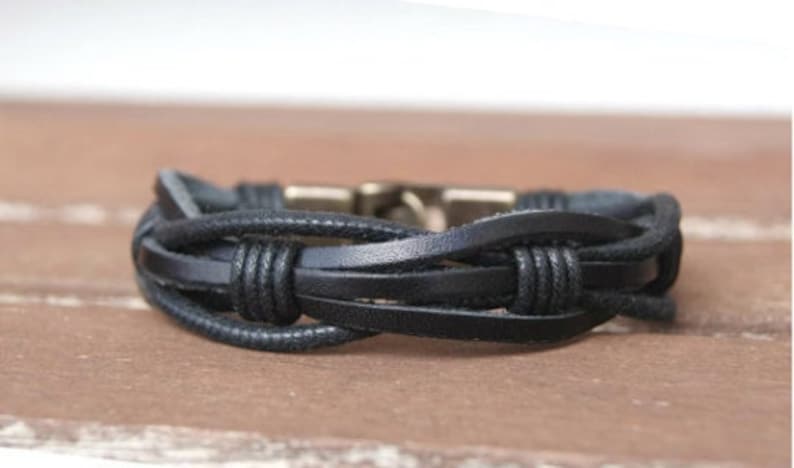 May include: A black leather bracelet with a braided design and a metal clasp.