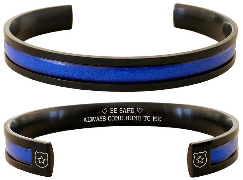 May include: Black stainless steel bracelet with a blue line and an engraved message: "BE SAFE ALWAYS COME HOME TO ME".