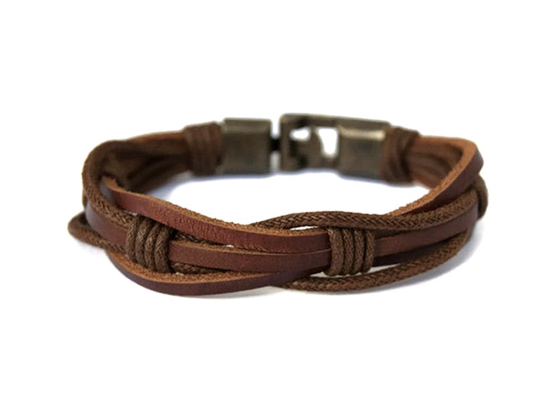 Men's brown leather bracelet featuring intertwined leather and cord elements, it has a rugged metal clasp. This handcrafted bracelet has a rustic, bohemian design, adding a touch of style to any outfit. Ideal as a Christmas or Birthday gift for men.
