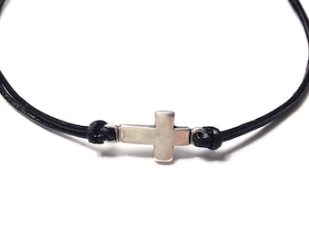 May include: A black leather cord necklace with a silver cross pendant.