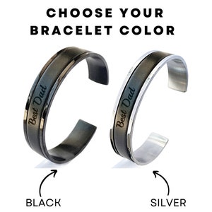 May include: Two stainless steel bracelets with a black and silver finish. Both bracelets have the words "Best Dad" engraved on them. The bracelet on the left is black and the bracelet on the right is silver.