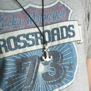 May include: A gray t-shirt with a vintage-style graphic of a motorcycle club patch. The patch features the text "Lucky Motorcycle Crossroads 73" and a stylized anchor.