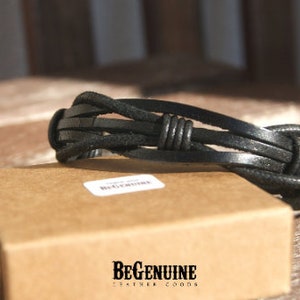 May include: Black leather bracelet with a braided design and a knot detail. The bracelet is on a brown box with the text "BeGenuine Leather Goods".