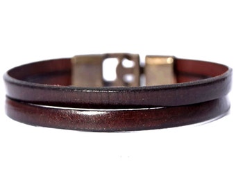 May include: A brown leather bracelet with a metal clasp. The bracelet is double-layered and has a simple design.
