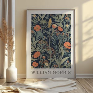 May include: A framed art print featuring a floral design with orange poppies, green foliage, and a yellow bird against a dark blue background. The print is labeled "WILLIAM MORRIS" in white text.