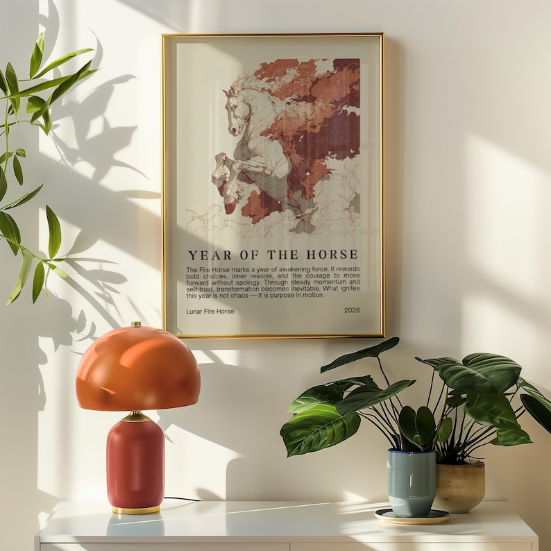 May include: A framed art print with a gold frame featuring a horse illustration with the text "YEAR OF THE HORSE". A red and orange table lamp sits on a white surface. Green plants in pots are also visible.