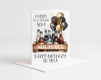 May include: A greeting card featuring a wooden crate filled with glass beer bottles, gold and black balloons, and the text CHEERS TO A SPECIAL SON! MICHAEL HAPPY BIRTHDAY TO YOU! The design includes gold glitter accents on a white background.