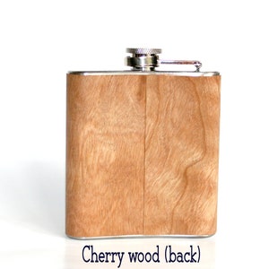 May include: A stainless steel flask with a cherry wood finish. The flask has a silver cap and a hinged lid. The back of the flask is shown in the image.
