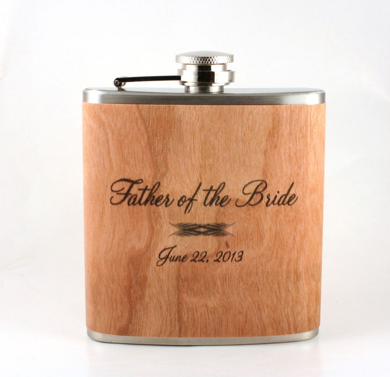 May include: A stainless steel flask with a wood veneer and a personalized inscription that reads "Father of the Bride" and "June 22, 2013".