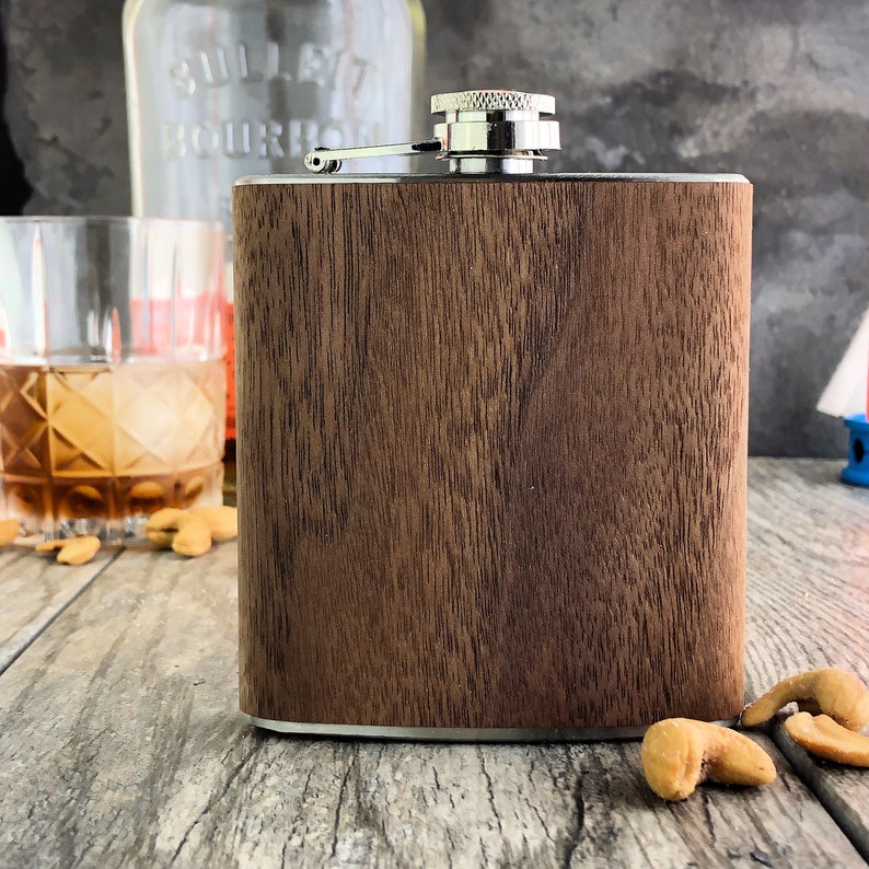 May include: A brown wooden flask with a silver lid and a silver hinge. The flask is sitting on a wooden surface.