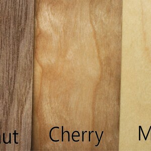 May include: Close-up of three wood samples: walnut, cherry, and maple. The wood grain is visible in each sample.