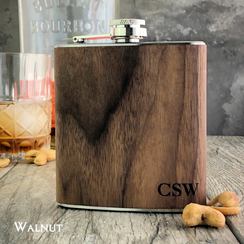 May include: A walnut wood flask with a silver top and engraved initials "CSW".