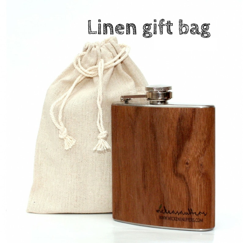 Pu&ograve; includere: Una fiaschetta di legno marrone con un tappo in acciaio inossidabile e un sacchetto regalo in lino. La fiaschetta ha il testo "wickensnuffers" e "www.wickensnuffers.com" inciso sul fondo.