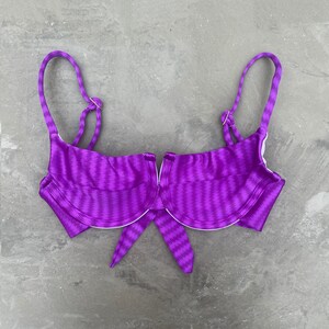 May include: Purple striped bikini top with underwire cups and a tie front.
