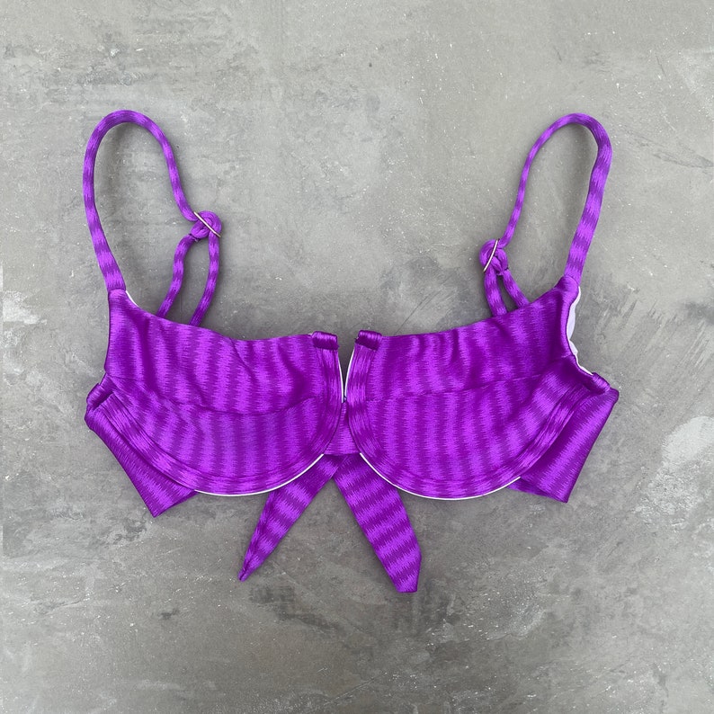 May include: Purple striped bikini top with underwire cups and a tie front.
