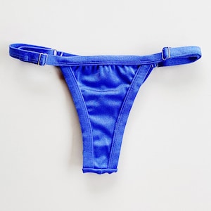 May include: A bright blue bikini bottom with adjustable straps. The straps are made of a thin, elastic material and have metal clasps.
