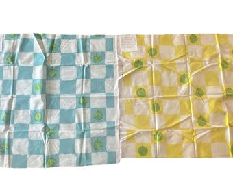 May include: Two fabric squares with a checkered pattern. One square is blue and white with green apples, the other is yellow and white with green apples.