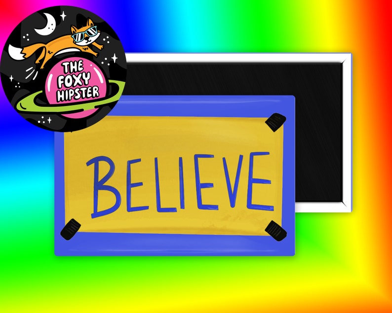 May include: A yellow and blue framed magnet with the word "BELIEVE" written in blue letters. The magnet is attached to a black framed magnet.