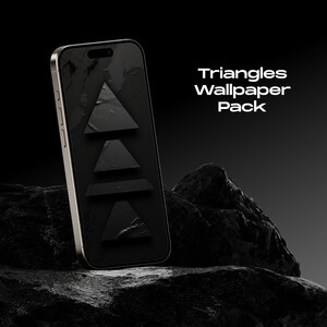 Könnte beinhalten: Ein schwarzes Smartphone mit goldenem Rahmen zeigt ein Hintergrundbild mit vier schwarzen Dreiecken auf schwarzem Hintergrund. Das Telefon liegt auf einem dunkelgrauen Stein. Der Text "Triangles Wallpaper Pack" wird über dem Telefon angezeigt.