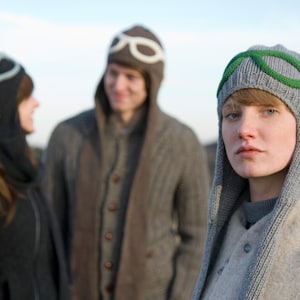 Pu&ograve; includere: Tre persone con cappelli invernali. La persona al centro indossa un cappello grigio con accenti verdi. La persona a sinistra indossa un cappello nero con un design bianco. La persona a destra indossa un cappello marrone con un paio di occhiali.