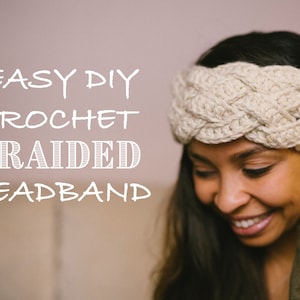 May include: A close-up of a woman wearing a crocheted braided headband. The headband is a light beige color and is made with a thick yarn. The headband is worn over the woman's forehead and covers her ears. The woman is smiling and looking down. The text "EASY DIY CROCHET BRAIDED HEADBAND" is written in white letters on a light pink background.