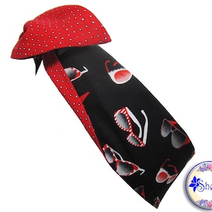 May include: A black and red fabric headband with a white polka dot pattern on the red side. The other side features a black background with a white and red sunglasses pattern. The headband is tied in a bow at the top.