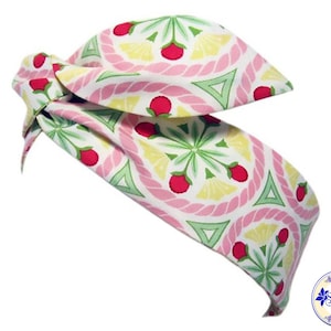 May include: A pink and green patterned headband with a knotted design. The pattern features pink and yellow circles with green leaves and red berries.