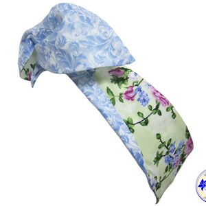 May include: A light blue and green floral headband with a bow. The headband is made of fabric with a floral pattern.