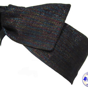 May include: A black headband with a large bow. The fabric has a shimmering, iridescent effect with flecks of multiple colors. The headband is shown against a white background. The brand name "Sheglily" is visible in the bottom right corner.