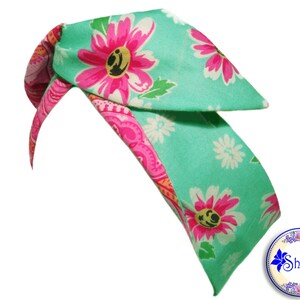 May include: A turquoise headband with a pink and white floral print. The headband is tied in a knot at the top and has a long, flowing tail.