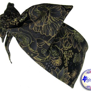 May include: Black fabric headband with a gold floral pattern. The headband is tied in a knot at the top.