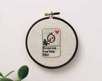 May include: Embroidered hoop art featuring a red heart, a green plant, and a red and white design. The text reads "Embroid... harlleee $60".