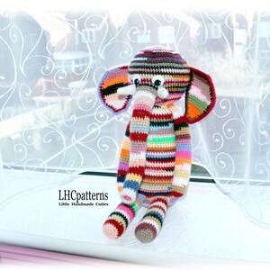 Puede incluir: Muñeco de elefante de ganchillo hecho a mano, colorido, con patrones de rayas en varios colores. El elefante tiene orejas grandes, una trompa larga y pequeños colmillos blancos. El texto "LHCpatterns Little Handmade Cuties" es visible.