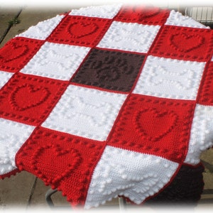 May include: A crocheted blanket with a checkered pattern of red, white, and brown squares. Each square features a raised heart design.