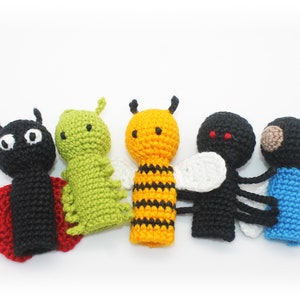 May include: Five crocheted finger puppets shaped like insects. The puppets are a ladybug, a caterpillar, a bee, a fly, and a blue bug. The puppets are all made with different colored yarn.