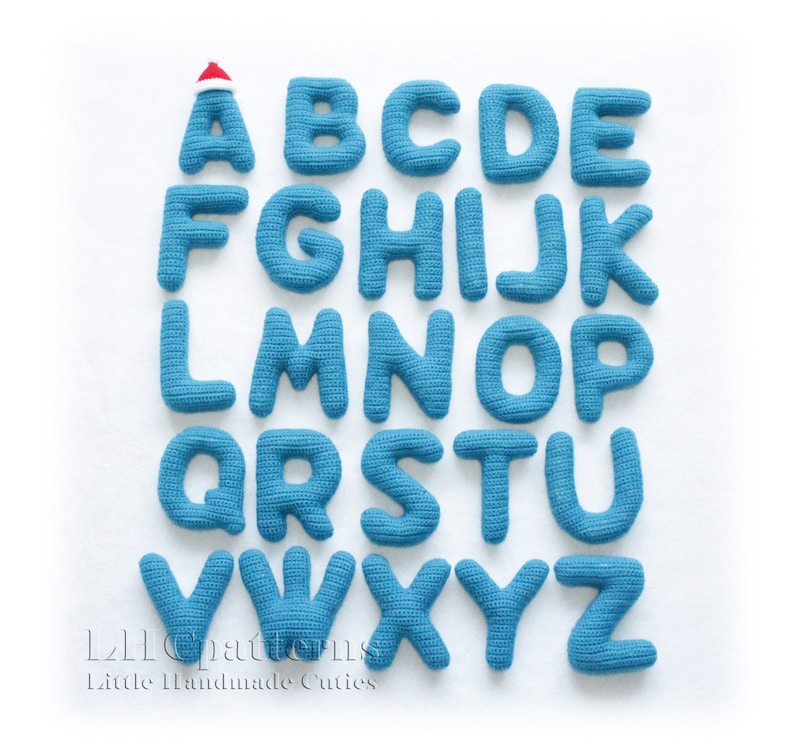 May include: A set of 26 blue crocheted letters, each letter is a separate piece. The letter A is wearing a red Santa hat. The letters are arranged in alphabetical order. The letters are on a white background.  The text "L2L patterns Little Handmade Cuties" is at the bottom of the image.