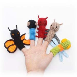 May include: Five finger puppets, each with a different design. The puppets are a butterfly with orange and black wings, a red ladybug, a brown and beige dragonfly, a blue and white bee, and a green and orange caterpillar.
