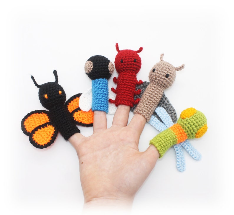May include: Five finger puppets, each with a different design. The puppets are a butterfly with orange and black wings, a red ladybug, a brown and beige dragonfly, a blue and white bee, and a green and orange caterpillar.
