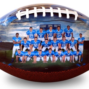 Op de afbeelding: Een voetbal met een foto van een voetbalteam dat blauwe shirts draagt met witte nummers. Het team staat voor een bord met de tekst "Pleasant Valley Bears".