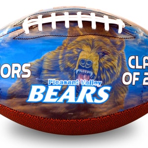 Op de afbeelding: Een bruine leren voetbal met een blauw, wit en bruin ontwerp. De voetbal heeft de woorden "Seniors", "Pleasant Valley Bears" en "Class of 2017" erop gedrukt.