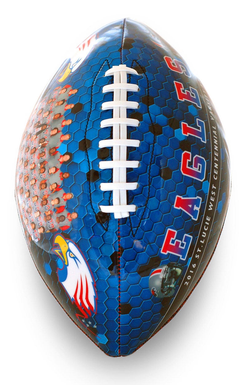Op de afbeelding: Een blauwe en zwarte voetbal met een wit veterspatroon. De voetbal heeft een zeshoekig patroon en de woorden "EAGLES" en "2016 ST. LUCIE WEST CENTENNIAL VARSITY" erop gedrukt. Er is een rood, wit en blauwe adelaar afbeelding op de voetbal.