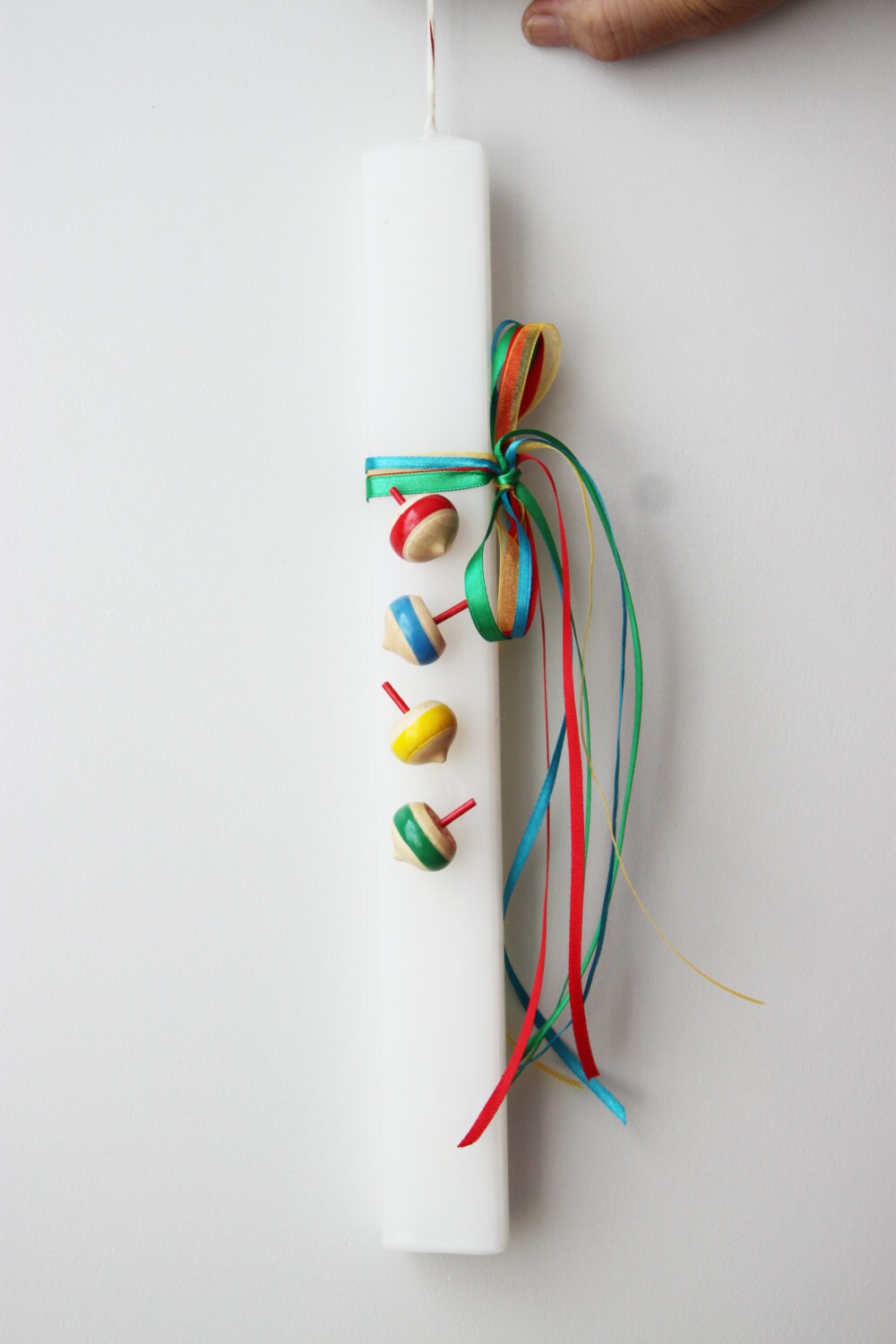 Spinning tops Easter candle, wooden spinning tops on flat, white candle