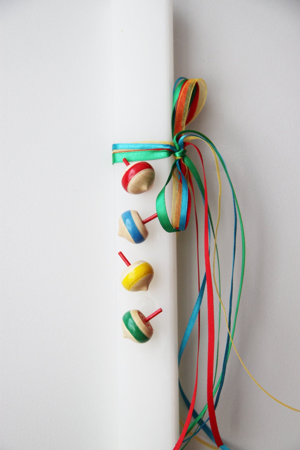 Spinning tops Easter candle, wooden spinning tops on flat, white candle