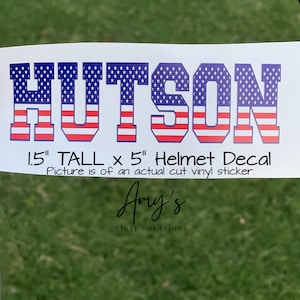 May include: A white vinyl decal with the name "HUTSON" in large, bold, block letters. The letters are decorated with an American flag pattern in red, white, and blue. The decal is 1.5 inches tall and 5 inches wide. The text below the decal reads "1.5" TALL x 5" Helmet Decal. Picture is of an actual cut vinyl sticker. Amy's VINYL CREATIONS".