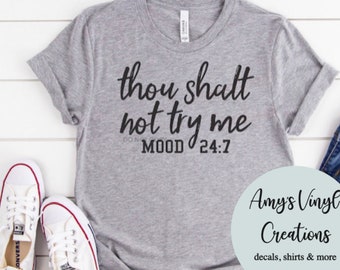 Peut inclure: Un t-shirt gris avec le texte "Thou shalt not try me MOOD 24:7" imprimé dessus. Le t-shirt est photographié sur une surface blanche avec une paire de baskets blanches.