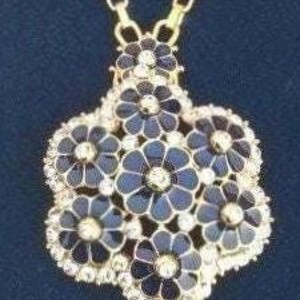 May include: A gold chain necklace with a pendant featuring a cluster of seven black enamel flowers with gold centers and clear crystal accents.